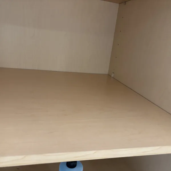 The same cabinet shelf after cleaning, with bare wood and no staining left