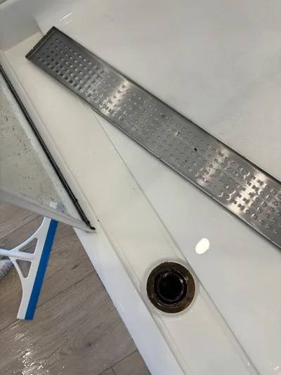 Close view of a cleaned linear shower drain channel and base