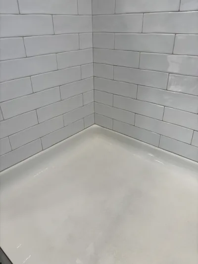 Shower corner with white subway tile and clean grout lines after a deep clean