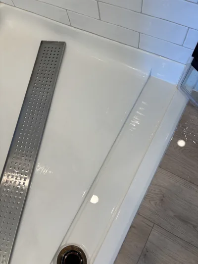 Linear shower drain cleaned and set back into a spotless shower base